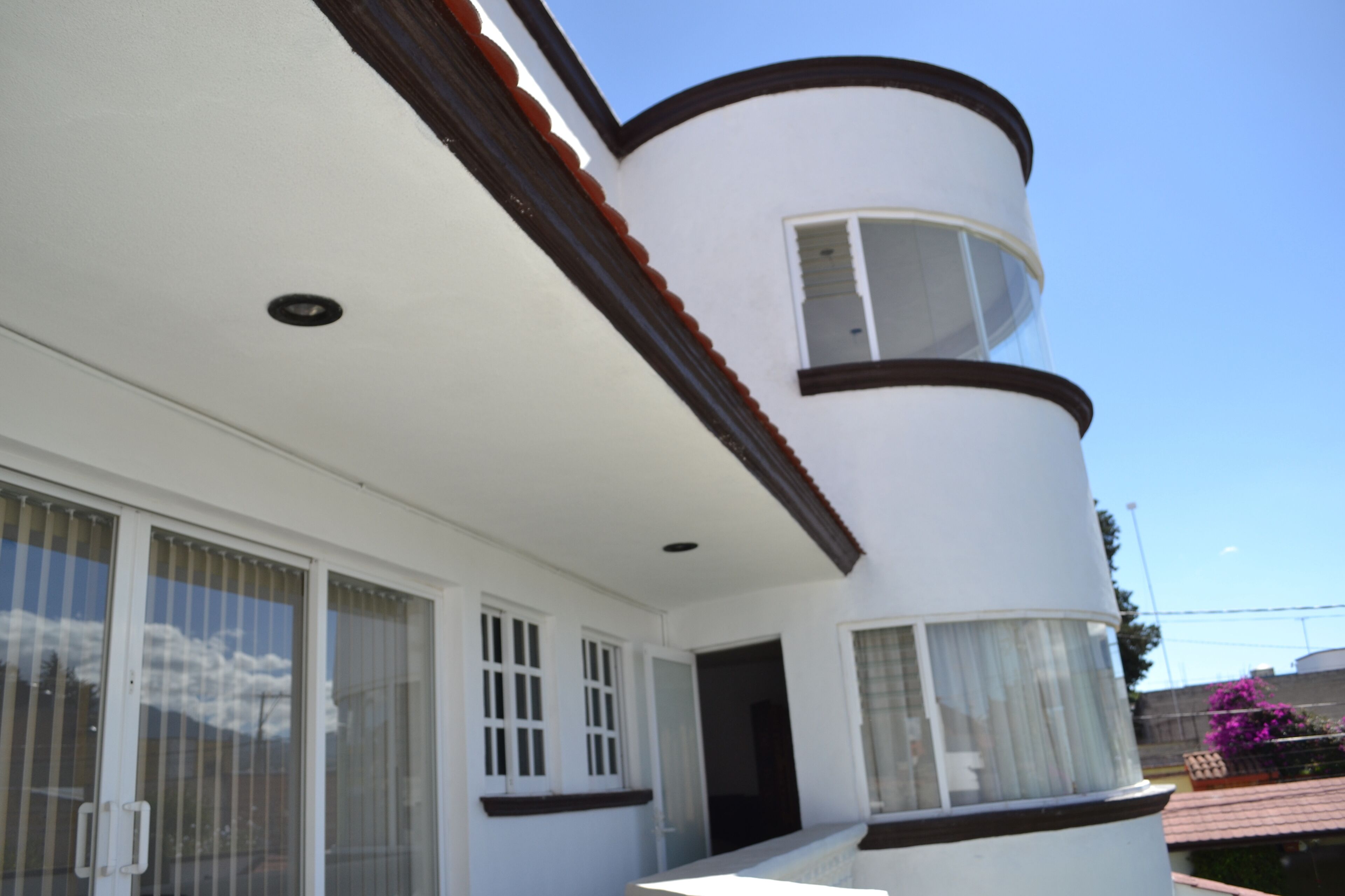 Um edifício branco com fachada curva, janelas grandes e uma porta.