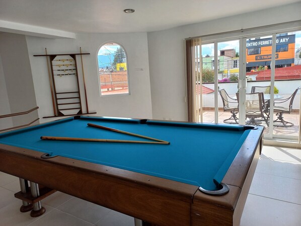 A pool table with pool cues, a ladder, and a window with a view of the outside. - Hotel La Aurora (Huamantla)