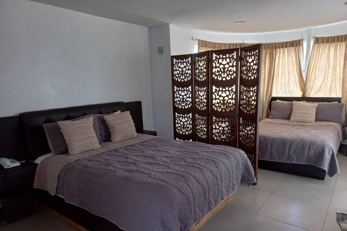 Un dormitorio con dos camas, un separador de madera y un teléfono en la mesita de noche.