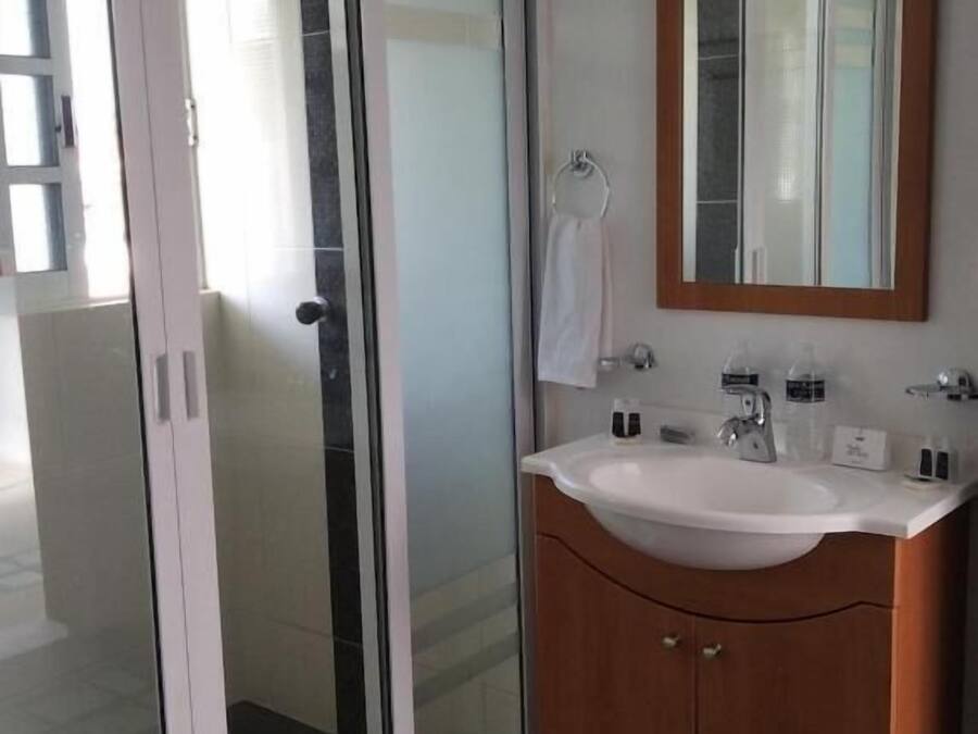 A modern bathroom with a glass shower enclosure, a wooden vanity with a sink, and a mirror.