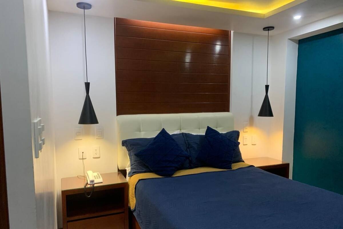 Un dormitorio con cama, mesitas de noche y un teléfono.