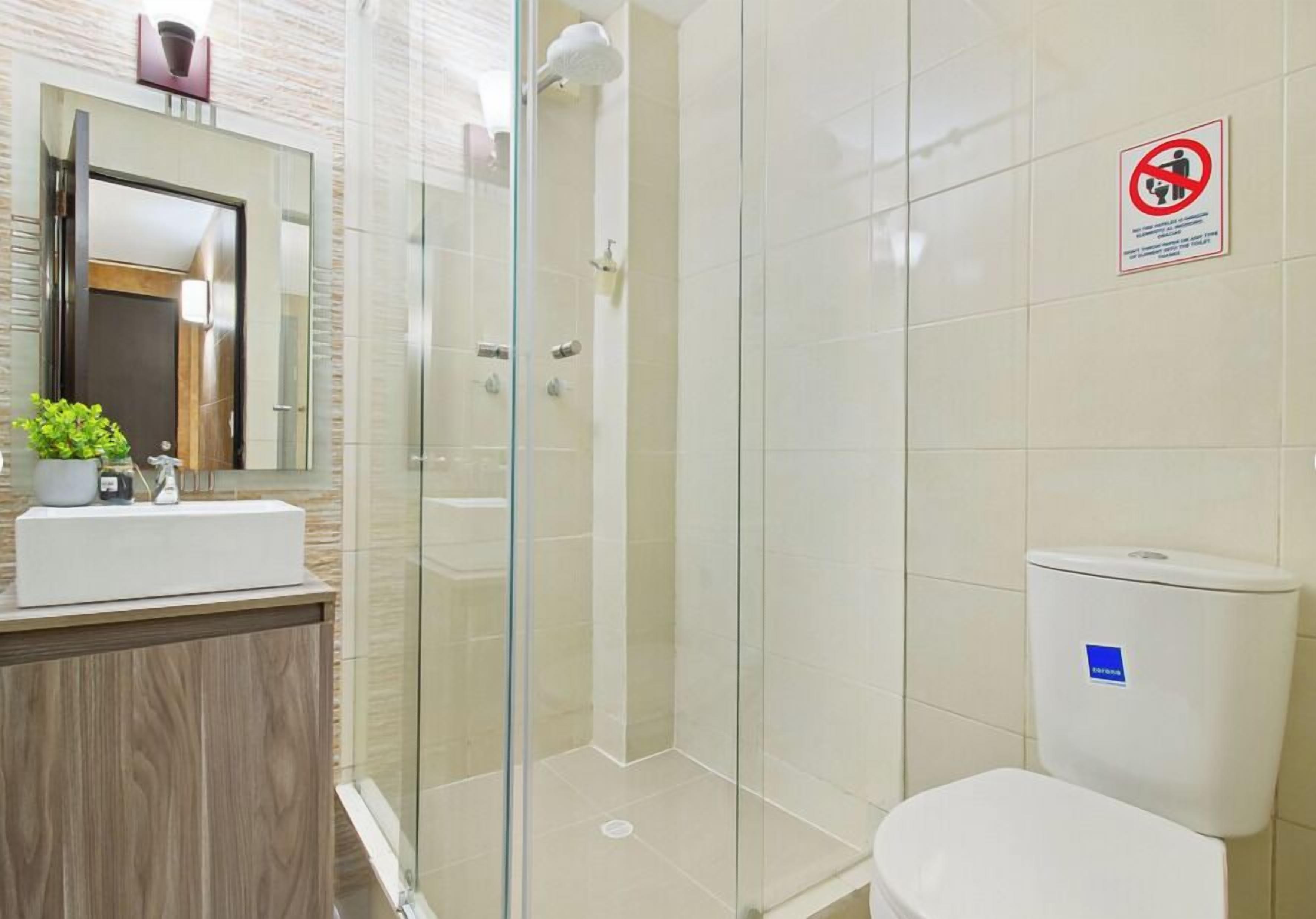 A modern bathroom with a glass shower enclosure, a white sink, and a toilet.