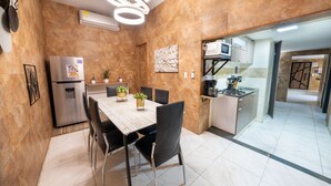 A modern kitchen with a built-in stove, microwave, and refrigerator. There is a dining area with a wooden table and chairs. - 5 Bedroom - 1 Block from Lleras - P2 (Medellín)