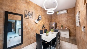 A modern dining area with a marble wall, a wooden table, black chairs, and a ceiling light fixture. - 5 Bedroom - 1 Block from Lleras - P2 (Medellín)