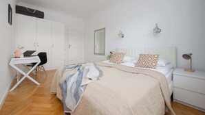 A bedroom with a bed, bedside table, lamp, and a desk with chair. - Apartment with Balcony in the Center | Air Conditioning and View (Warszawa)
