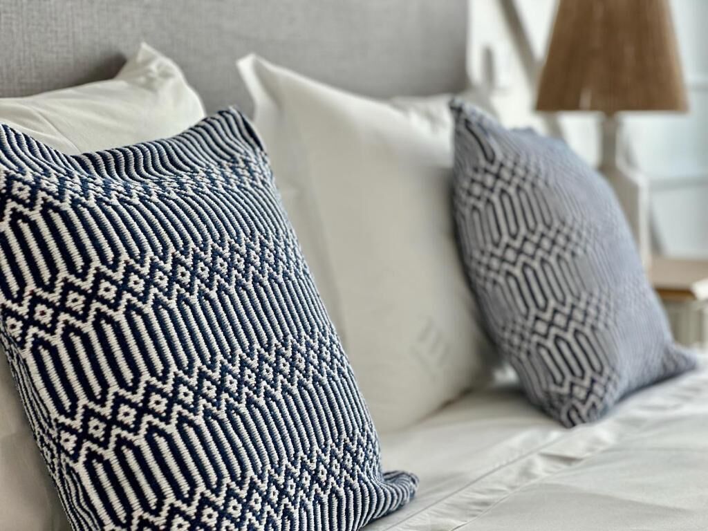 Ein Bett mit weißer Bettwäsche und zwei Kissen mit Muster.