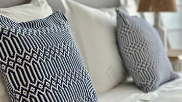 Ein Bett mit weißer Bettwäsche und zwei Kissen mit Muster.