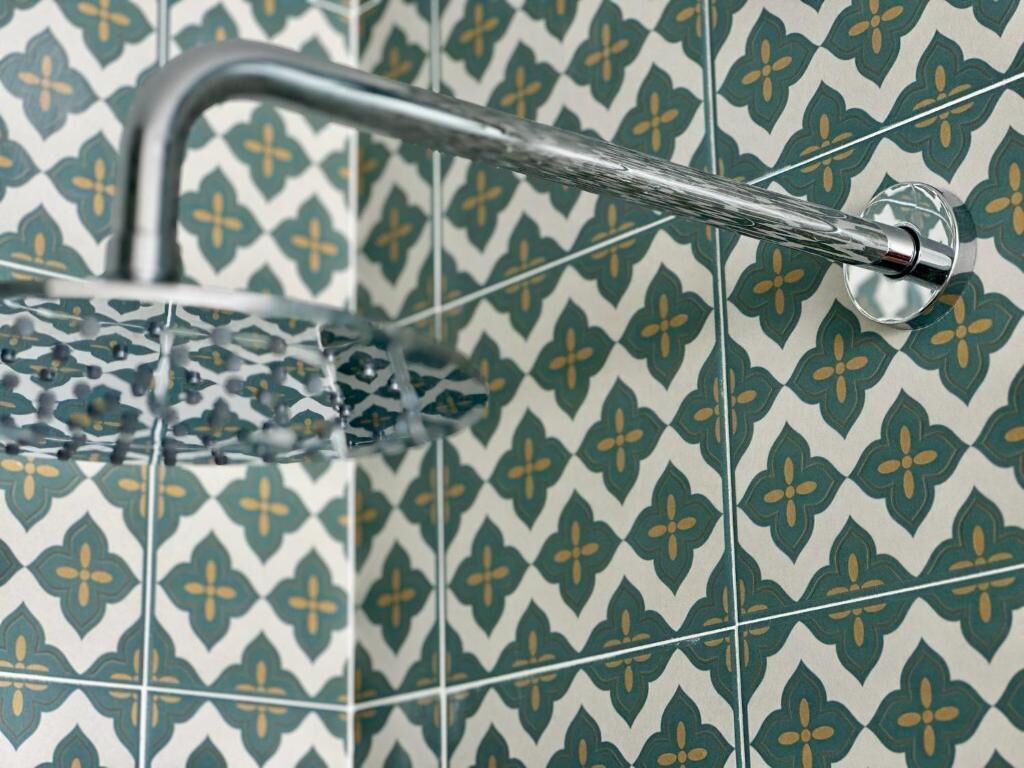 Une douche avec un robinet chromé et un pare-douche en verre.