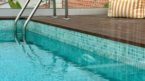 Una piscina con borde de azulejos y zona de cubierta de madera.