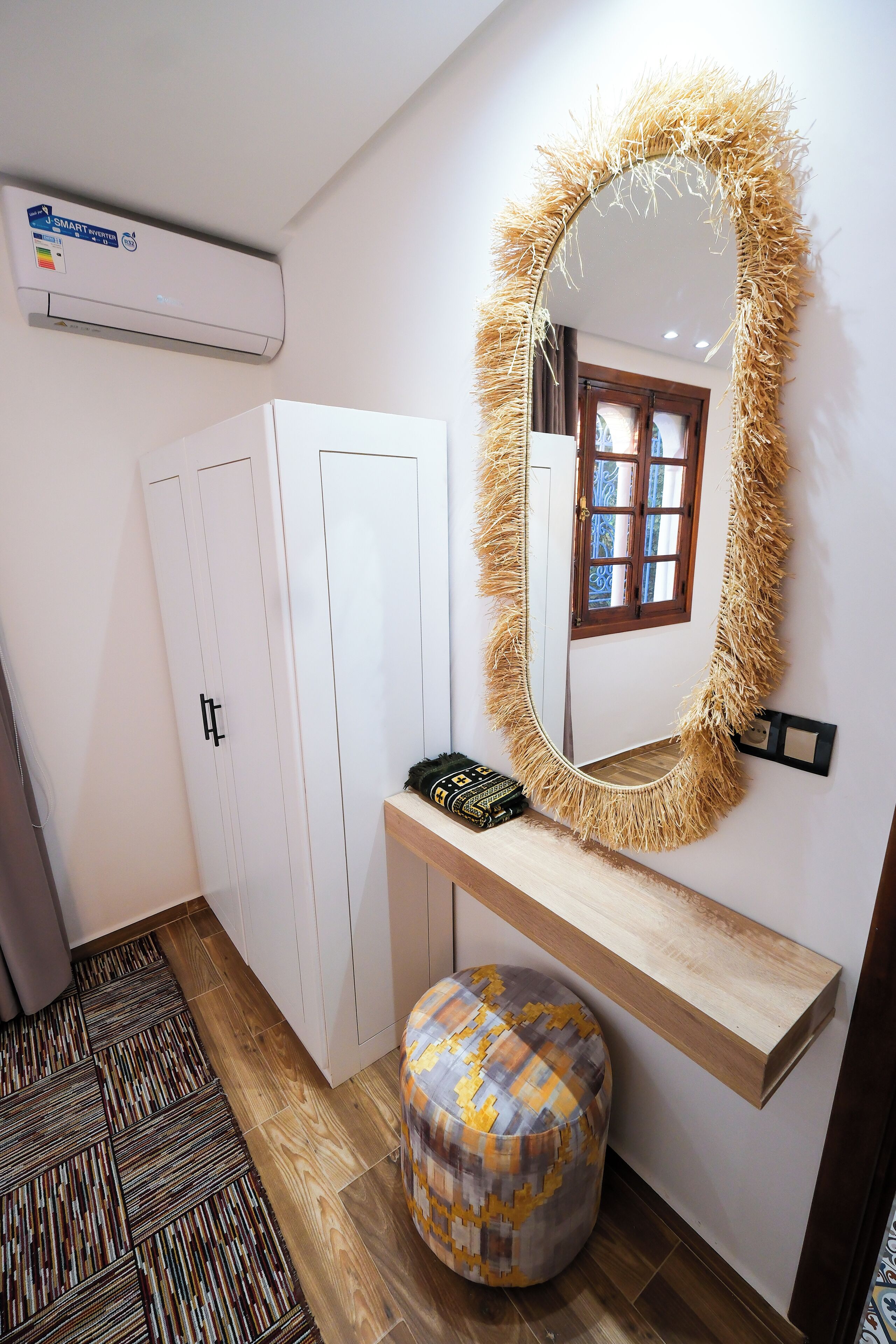 Une pièce avec un miroir, une armoire, un banc et un tapis à motifs.
