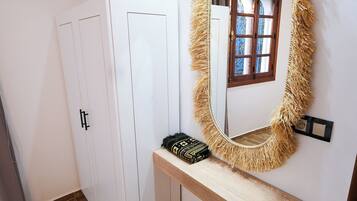 Une pièce avec un miroir, une armoire, un banc et un tapis à motifs.