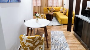 A modern living room with a yellow sofa, a dining table with chairs, and a kitchen area. - Cozy 1-Bedroom Studio with AC in beautiful Chefchaouen (Chefchaouen)