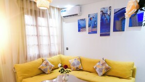 A yellow sofa with patterned cushions, a wooden coffee table, and a hanging light fixture. - Cozy 1-Bedroom Studio with AC in beautiful Chefchaouen (Chefchaouen)