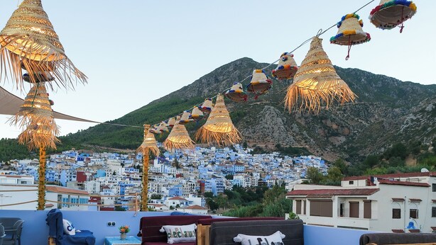 A rooftop terrace with wooden furniture, striped cushions, and hanging lanterns. - Cozy 1-Bedroom Studio with AC in beautiful Chefchaouen (Chefchaouen)
