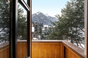 Een houten balkon met uitzicht op besneeuwde bomen en bergen.