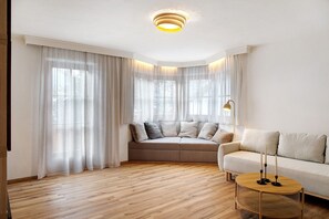 Een moderne woonkamer met een bank, een rond houten bijzettafeltje en een lamp.