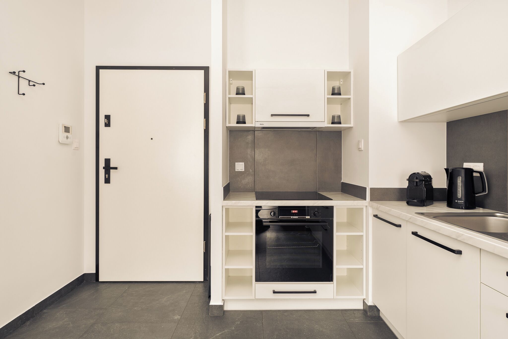 Eine kompakte Küchenzeile mit integriertem Backofen, einer Kaffeemaschine und einem Bosch-Kaffeekocher.