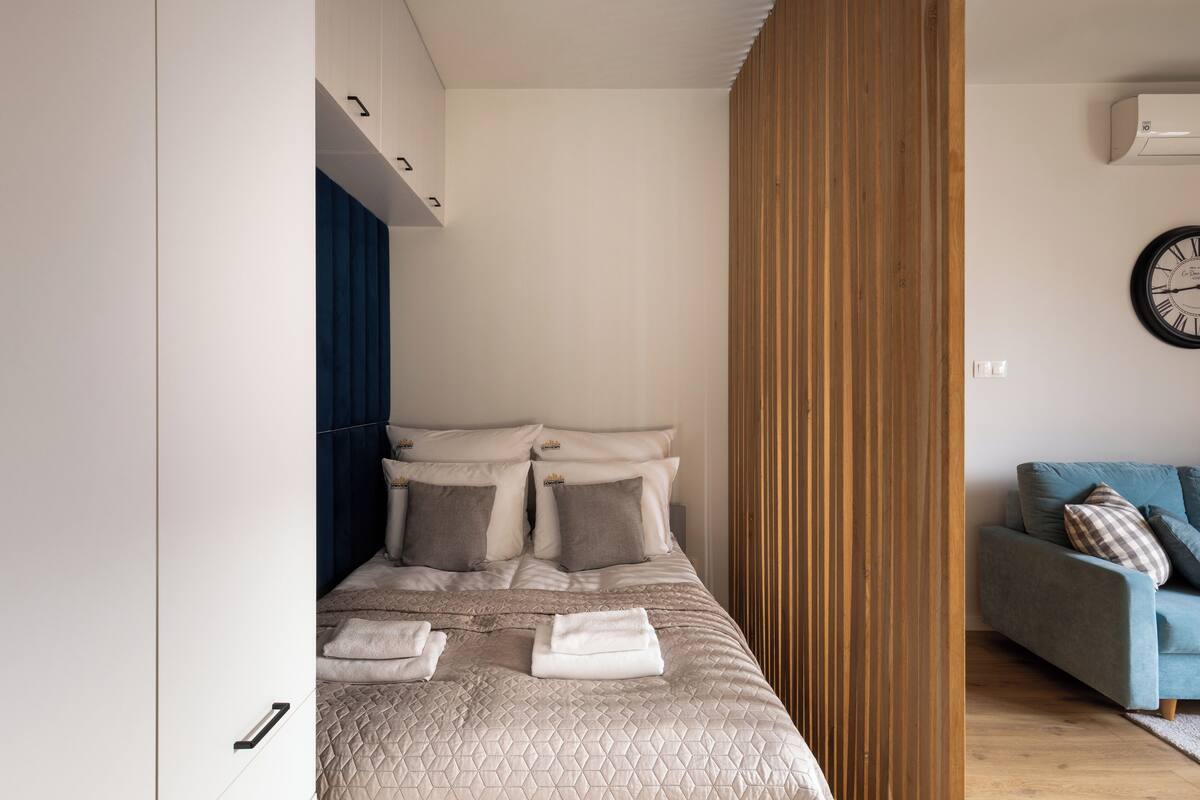 Une chambre moderne avec un lit bien fait, un canapé bleu et une cloison en bois.