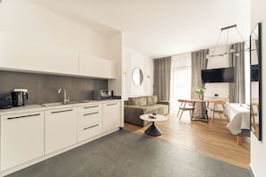 A modern kitchen with white cabinets, a coffee maker, and a microwave. - Rakowicka Suite & Parking by Downtown Apartments (Kraków)