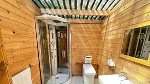 A wooden cabin bathroom with a glass shower enclosure, a toilet, and a sink. - Cosy Off-Grid Stargazing Dome in the Jurassic Coast with optional Hot Tub & Sauna (Devon)