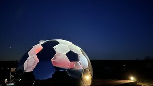 A large, illuminated dome structure at night. - Cosy Off-Grid Stargazing Dome in the Jurassic Coast with optional Hot Tub & Sauna (Devon)