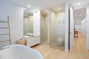 Un baño moderno con una bañera independiente, un espejo grande y una ducha con cerramiento de vidrio.