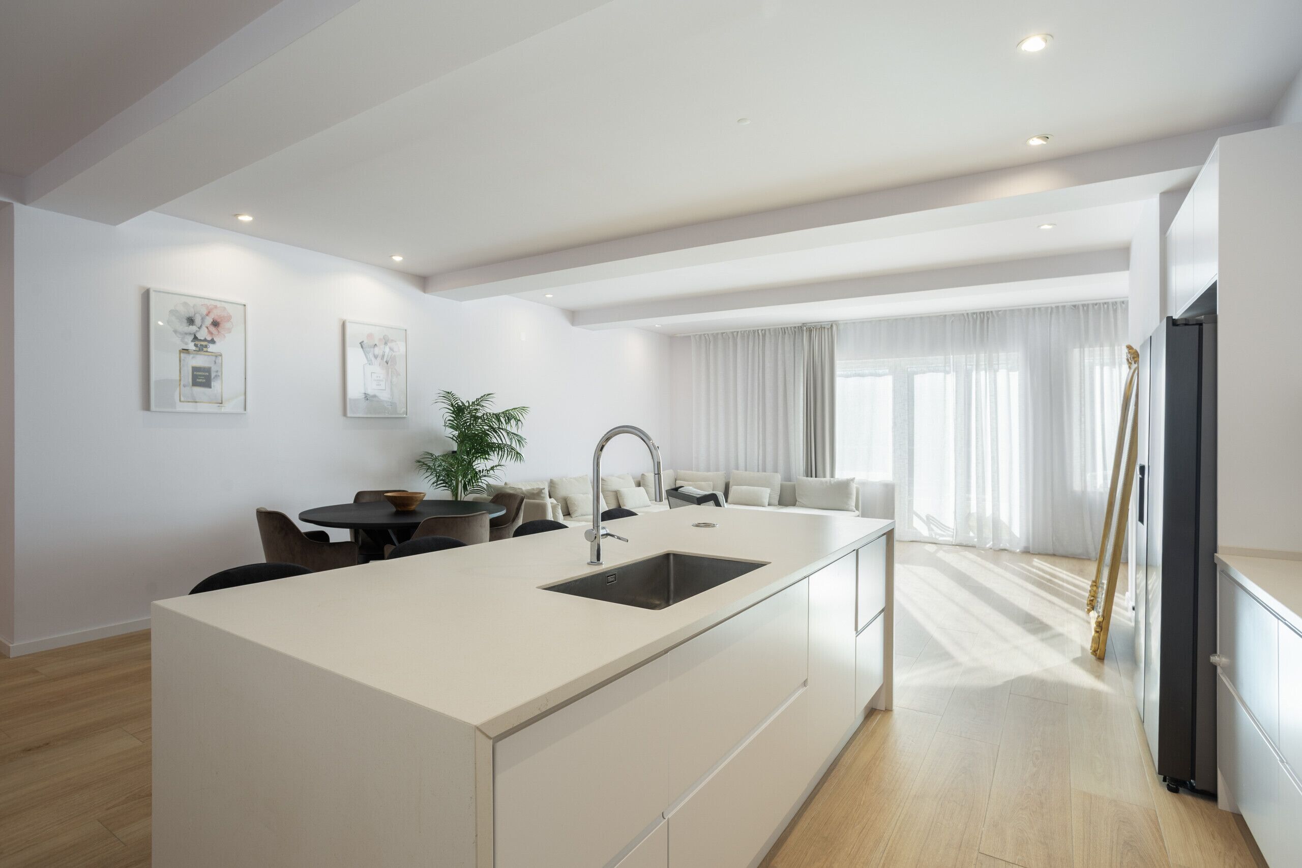 Een moderne keuken met een centraal eiland, inbouwapparatuur en een eethoek met een tafel en stoelen.
