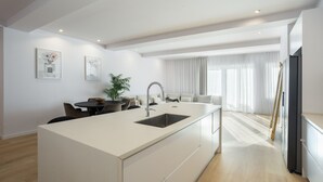 A modern kitchen with a central island, built-in appliances, and a dining area with a table and chairs. - Marques DE Pombal Grand Prestige (Lisbon)