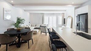 A modern kitchen with a large island, a dining area with a round table and chairs, and a living area with a sofa and chairs. - Marques DE Pombal Grand Prestige (Lisbon)