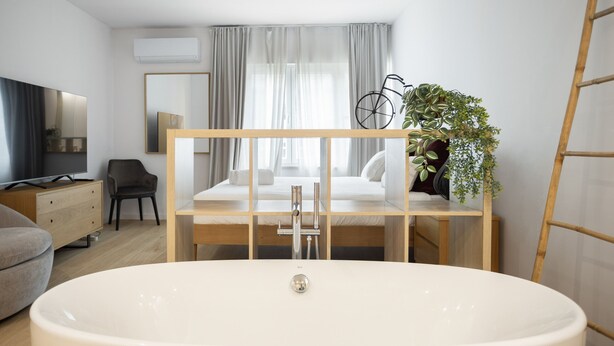 A modern bathroom with a freestanding bathtub, a wooden vanity, a mirror, and a potted plant. - Marques DE Pombal Grand Prestige (Lisbon)