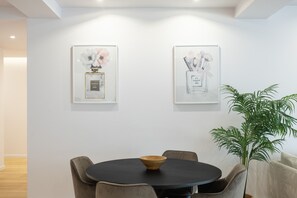 Un comedor con una mesa redonda, sillas y un tazón. Hay dos obras de arte enmarcadas en la pared.