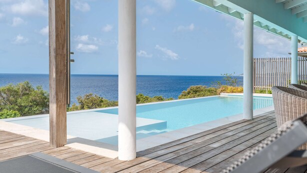 A wooden deck with a pool overlooking the ocean.