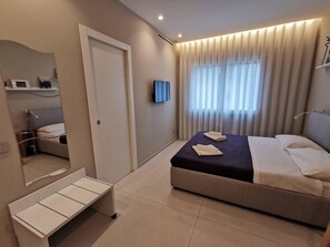Une chambre moderne avec un lit, des tables de chevet, un miroir et un téléviseur.