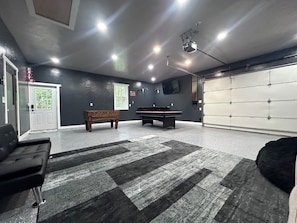 Une pièce avec une table de billard, un canapé, un tapis et une porte de garage.