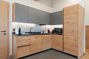 Une cuisine moderne avec des meubles en bois, un plan de travail noir et un four à micro-ondes encastré.
