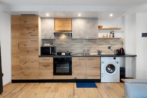 Eine moderne Küche mit Holzausbau, integriertem Backofen, Waschmaschine und einer Spüle mit Arbeitsfläche.