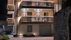 En byggnad med flera våningar, balkonger, ett garage och en mur av sten.