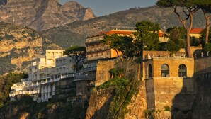 A hotel with multiple balconies, a stone facade, and a view of the surrounding mountains. - Casa Lalen,
Luxury Apartment with Jacuzzi and Terrace in the Heart of Sorrento. (Sorrento)