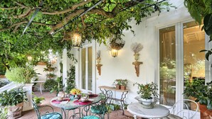 An outdoor patio with tables and chairs, surrounded by potted plants and hanging baskets. - Casa Lalen,
Luxury Apartment with Jacuzzi and Terrace in the Heart of Sorrento. (Sorrento)