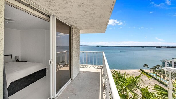 Un balcon avec un lit, une vue sur la mer et un espace piscine.