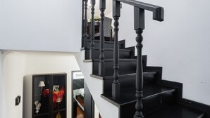 Un escalier avec des rampes noires et des marches en bois menant à l’étage supérieur.