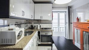 Une cuisine moderne avec des meubles blancs, un plan de travail en granit, une cuisinière, un four et un four à micro-ondes.