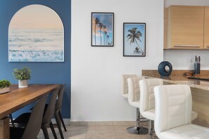 Una cocina moderna con una mesa de madera, taburetes de bar y cuadros en la pared.