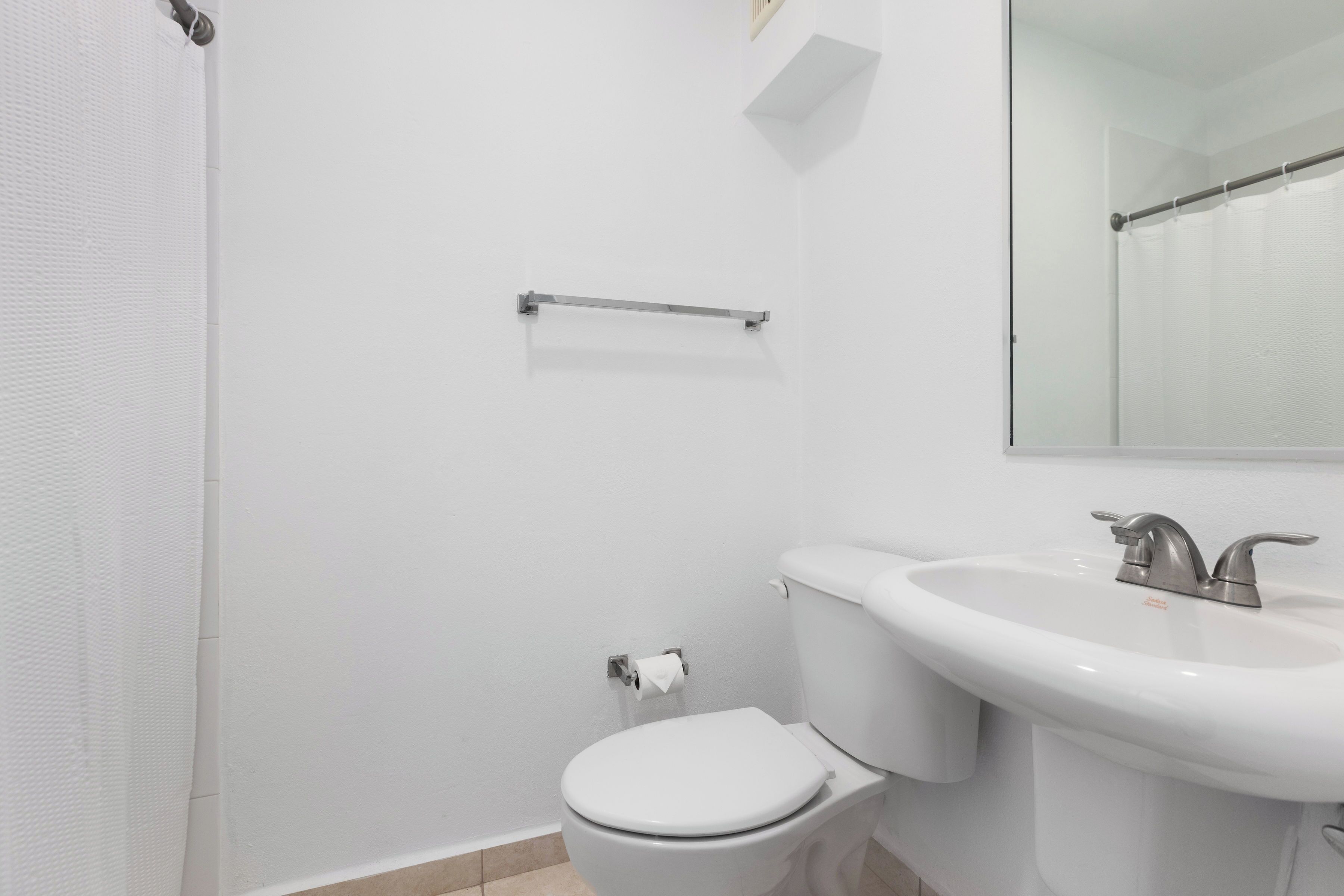 A bathroom with a white toilet, a sink, and a mirror.