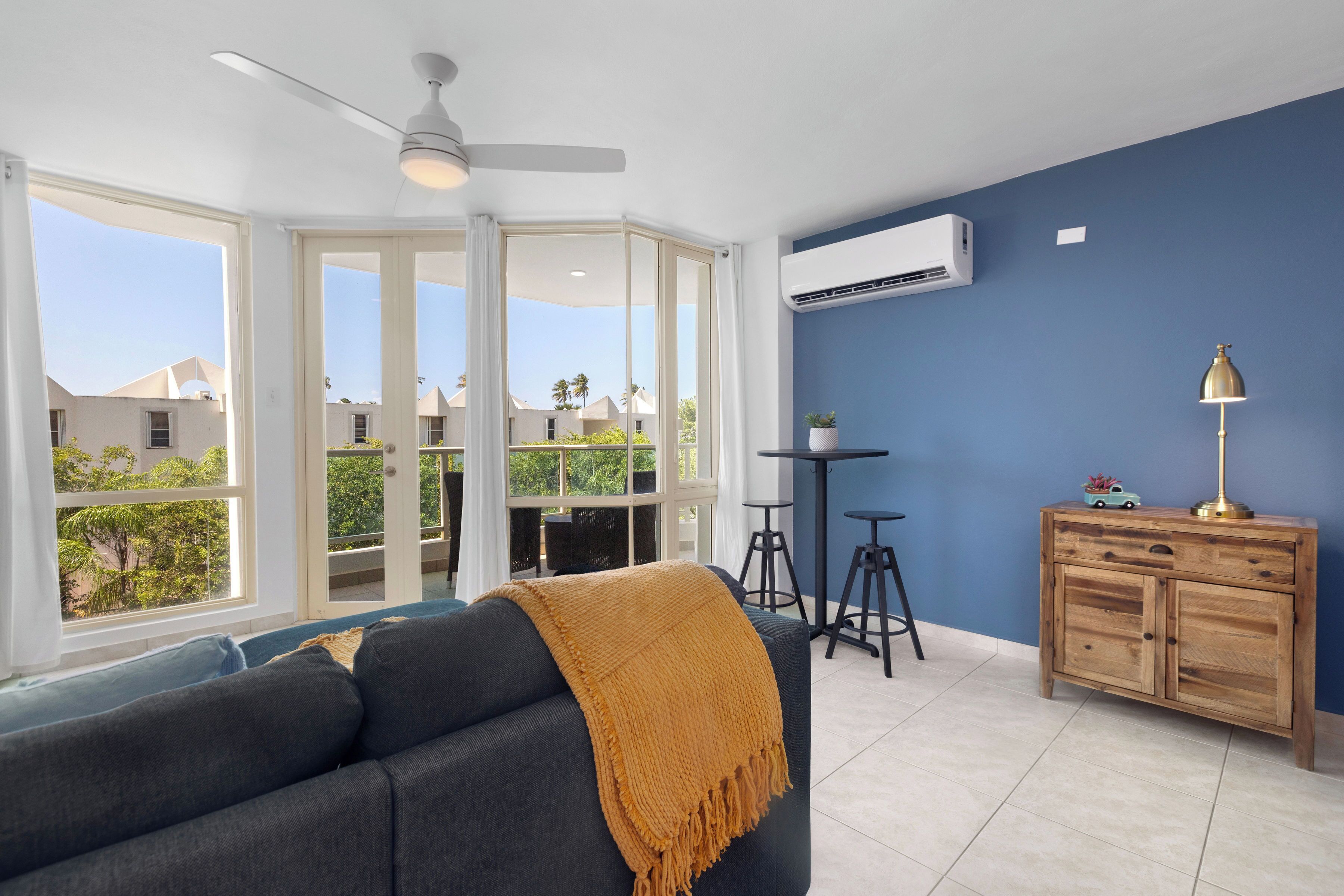 Un soggiorno moderno con un divano blu, un mobile in legno e una ventola a soffitto.