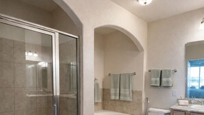 Ein Badezimmer mit einer Duschkabine, einer freistehenden Badewanne, einer Toilette und einem Waschtisch mit Spiegel.