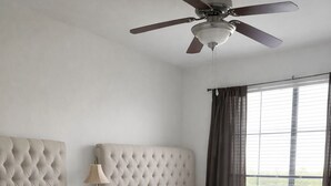 Ein Hotelzimmer mit zwei Betten, einem Deckenventilator und Blick ins Freie durch große Fenster.