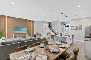 Un espacio habitable moderno con comedor, cocina y una escalera que sube a un nivel superior.
