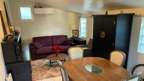 Uma sala de estar acolhedora com uma mesa de jantar de madeira, um sofá e um armário.