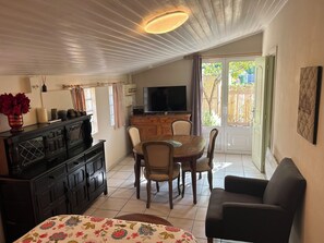 Un coin repas avec une table et des chaises en bois, un téléviseur et un meuble contenant des objets décoratifs.